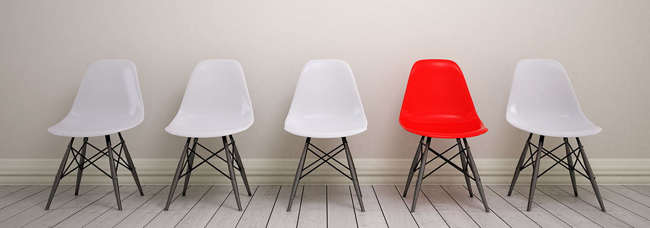 Ein roter leerer Stuhl zwischen vier roten leeren Stühlen