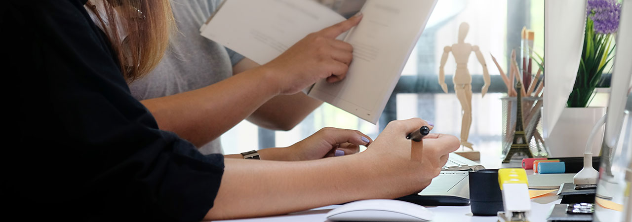 Eine Person zeigt auf eine Zeile in einem Magazin, eine andere Person schreibt etwas